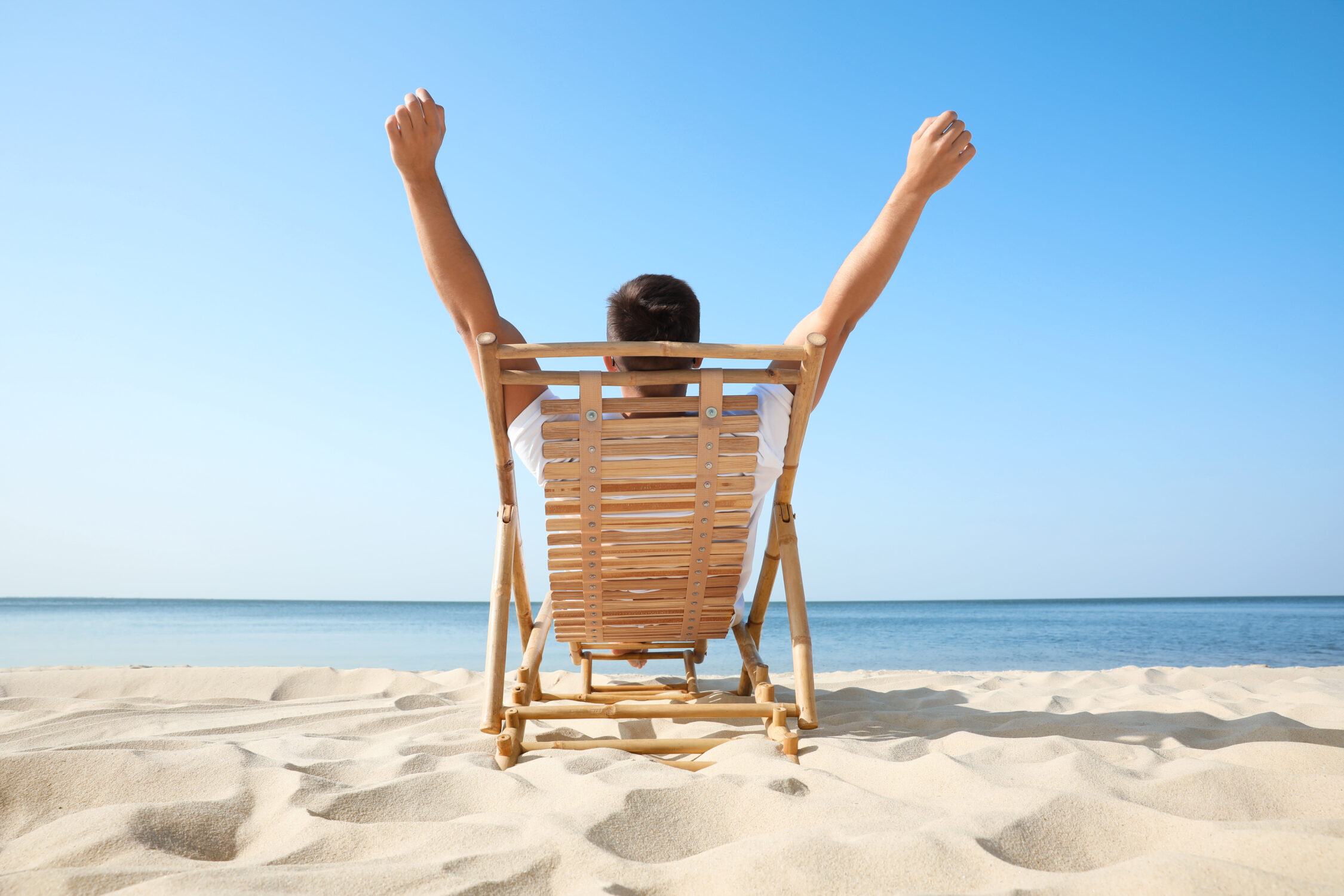man in lounge chair stretching at the beach